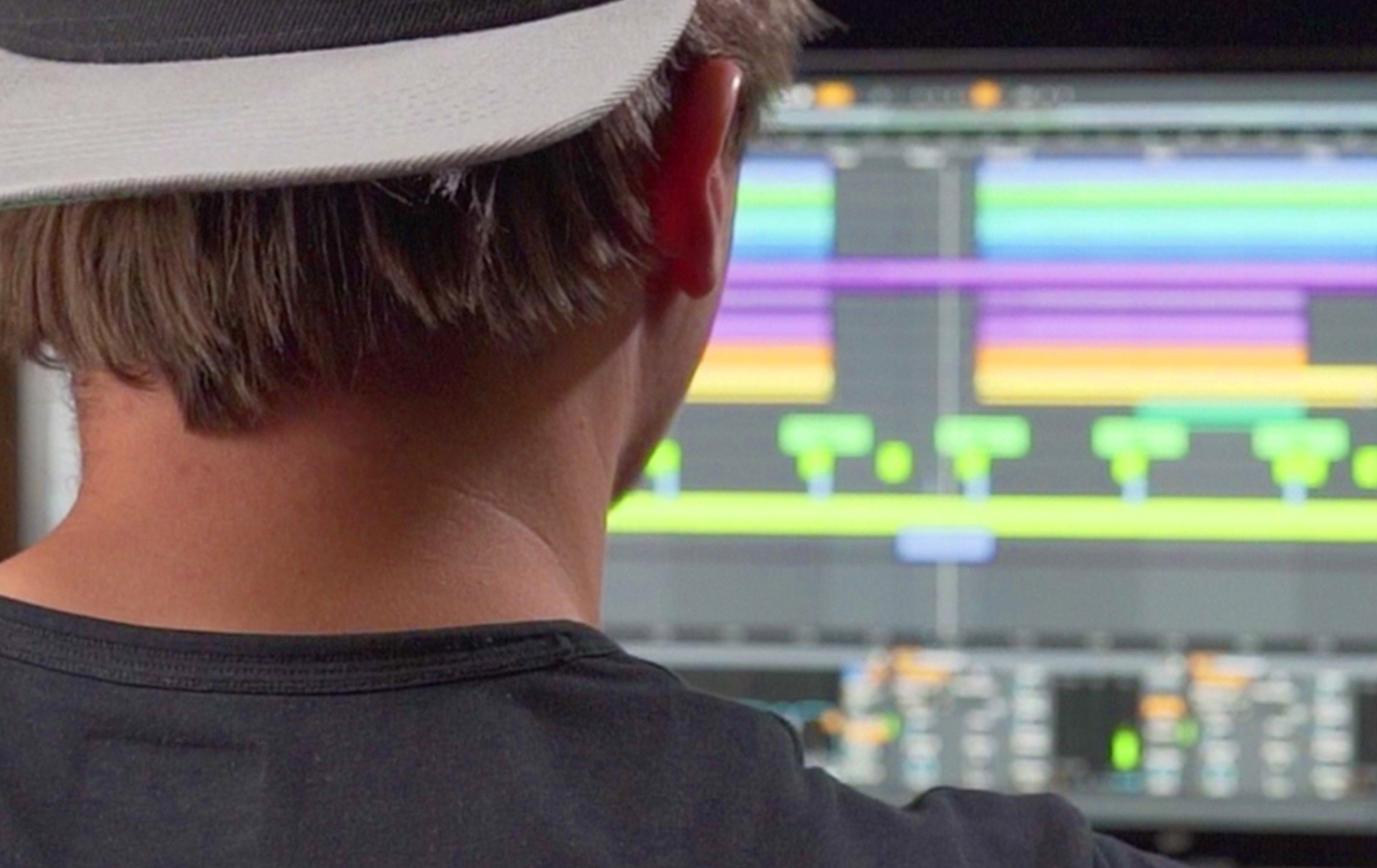 Producer at the studio desk with an Ableton Live arrangement on screen